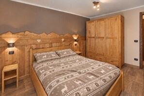 Una cama de madera con colcha estampada, dos mesitas de noche y un armario con cabecera de madera.