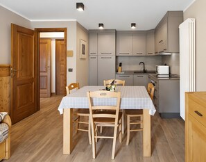 A modern kitchen with grey cabinets, a white countertop, and a built-in oven. - Apartment '4061 Maison Gérard Torre del Gran San Pietro – Svegliarsi tra le Vette' with Balcony, Shared Garden and Wi-Fi (Cogne)