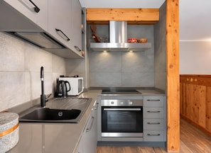 Una cocina compacta con horno integrado, hornilla y microondas.