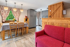 Un comedor con una mesa dispuesta para cuatro, un sofá rojo y un mueble de madera con un letrero.