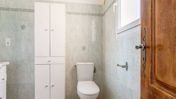 A bathroom with a toilet, a cabinet, and a wooden door.