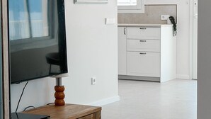 Un soggiorno moderno con una TV a schermo piatto su un supporto in legno, una piccola mensola e una finestra con vista.