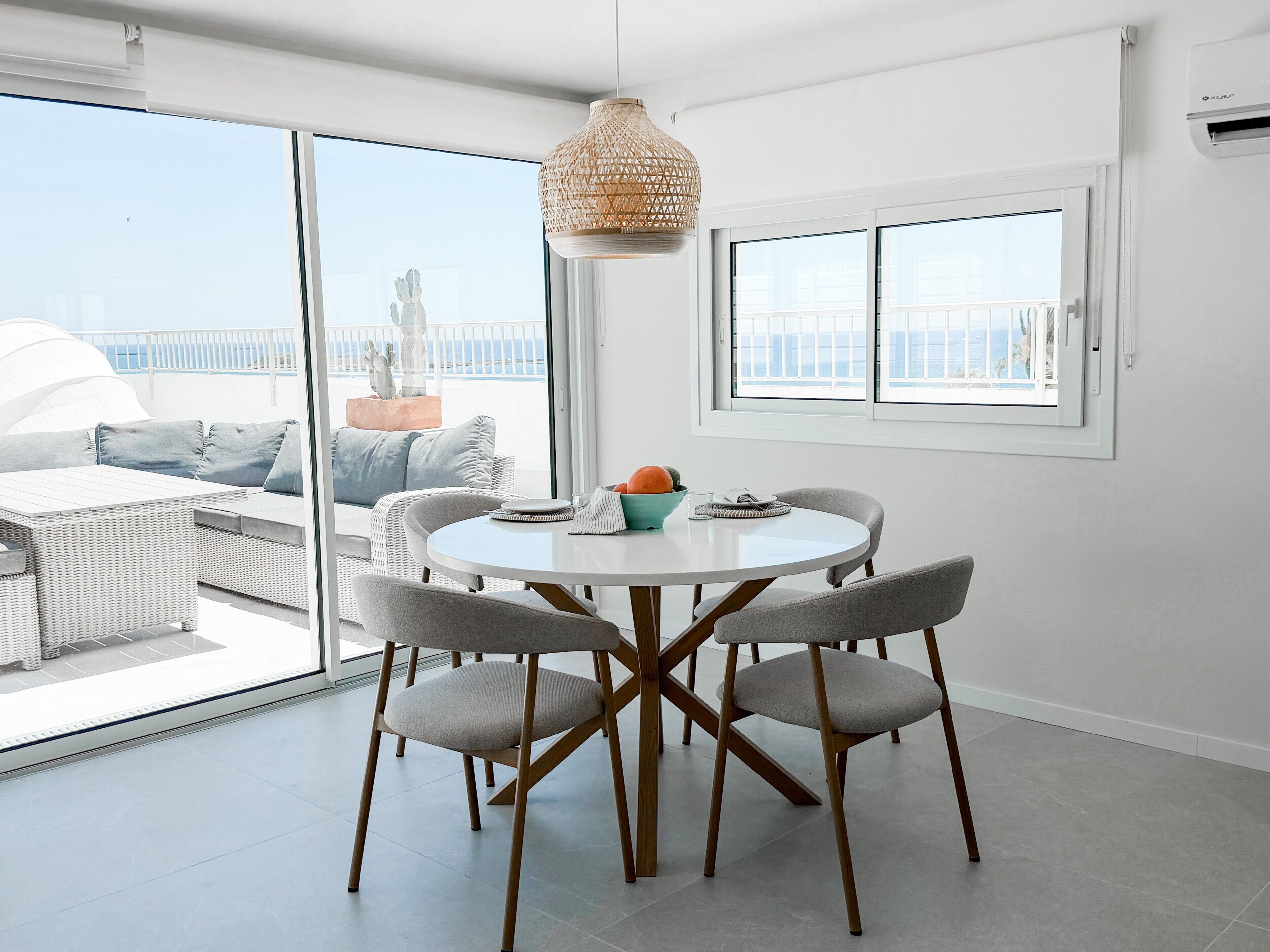 Un coin repas avec une table ronde, quatre chaises et un luminaire suspendu.
