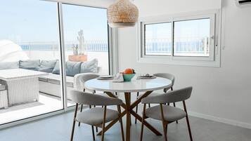 Un coin repas avec une table ronde, quatre chaises et un luminaire suspendu.
