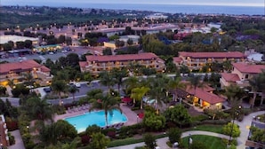 A resort with multiple buildings, a swimming pool, and lush landscaping.
