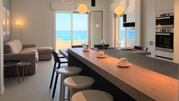 A modern kitchen with a central island, bar stools, and a view of the ocean. - Apartment 'Gallipoli Waterfront' with Sea View, Balcony and Air Conditioning (Gallipoli)
