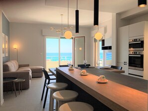 Cozinha moderna com ilha central, banquetas e vista para o oceano.