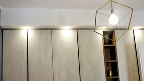 A room with a geometric light fixture, a built-in shelf, and a large wardrobe with vertical panels. - Apartment 'Gallipoli Waterfront' with Sea View, Balcony and Air Conditioning (Gallipoli)