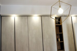 A room with a geometric light fixture, a built-in shelf, and a large wardrobe with vertical panels.
