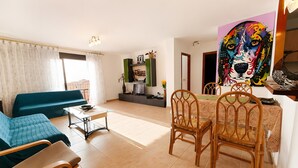 Una sala de estar con sofá, sillas, una mesa de comedor y un cuadro.