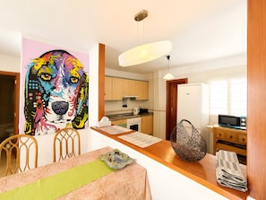 A modern kitchen with wooden cabinets, a microwave, and a dining area with a table and chairs.