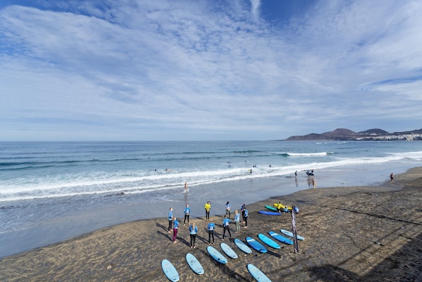 A beach with surfboards lined up, a group of people, and the ocean.