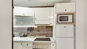 A compact kitchen with white cabinets, a microwave, a built-in oven, and a sink. - Apartment 'La Casa De Utiaca 28' with Wi-Fi (Las Palmas de Gran Canaria)