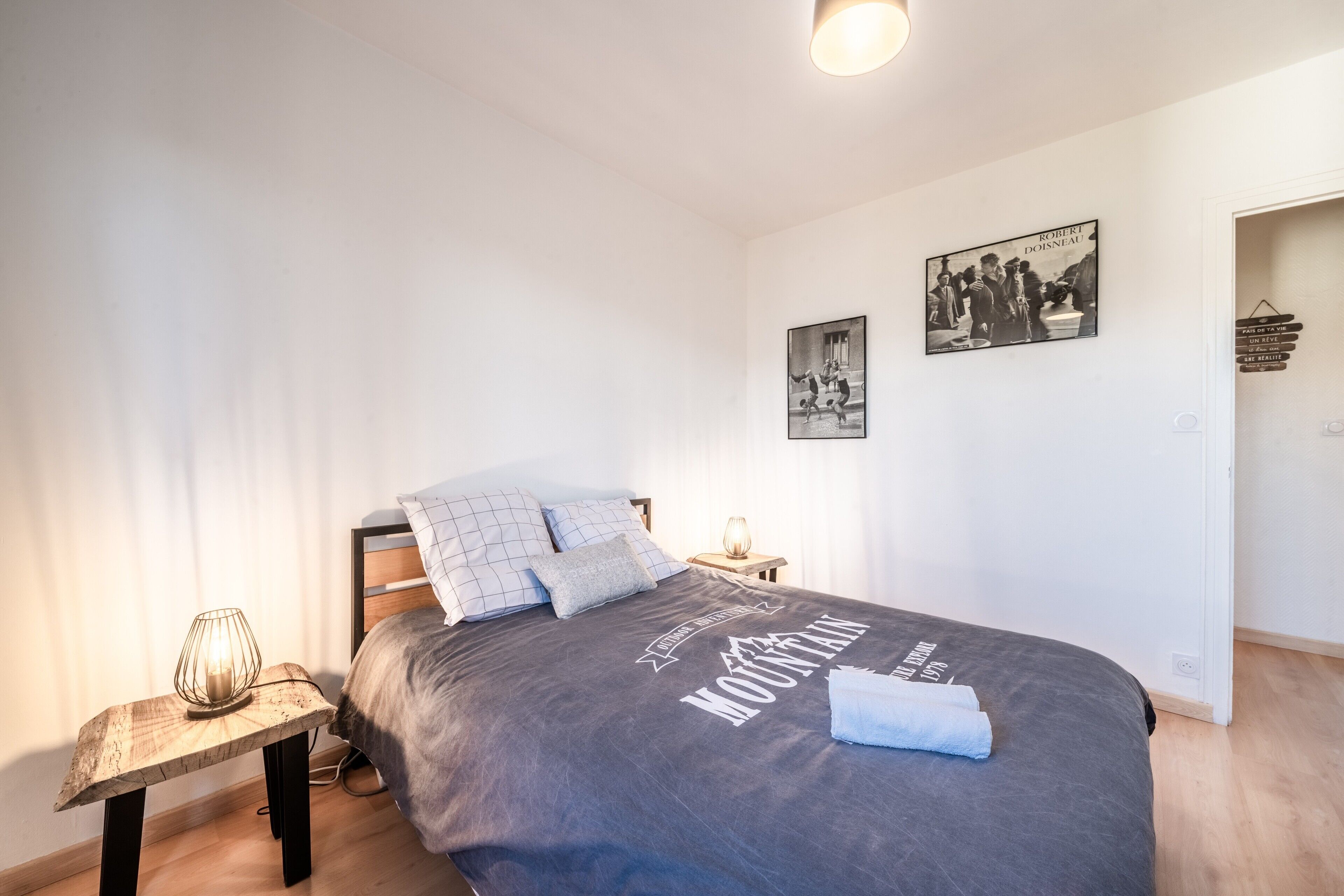 A bedroom with a bed, bedside tables, and wall art.