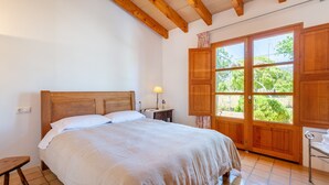 A bedroom with a wooden bed, a nightstand, a lamp, and a large window with a view of greenery. - Rural House 'Faustina' with Private Pool, Private Terrace, and Wi-Fi (Selva)