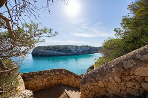 A stone staircase leading to a coastal view with a clear sky.