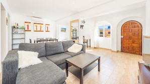 A living room with a sectional sofa, a coffee table, and a dining area with chairs and a table. - Holiday Home 'Casa Noa' with Private Pool, Wi-Fi and Air Conditioning (Romàntica)