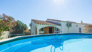 A swimming pool with a clear blue water, a ladder, and a small building with a tiled roof in the background. - Holiday Home 'Casa Noa' with Private Pool, Wi-Fi and Air Conditioning (Romàntica)