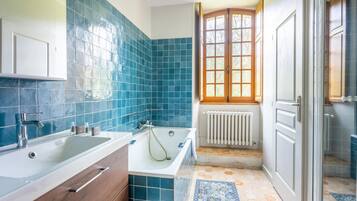 Een badkamer met een bad, een wastafel en een raam met uitzicht op bomen.