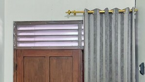 A wooden door with a window above it, a curtain, and an air conditioning unit on the wall. - Wisma Sanggrahan (Bantul)