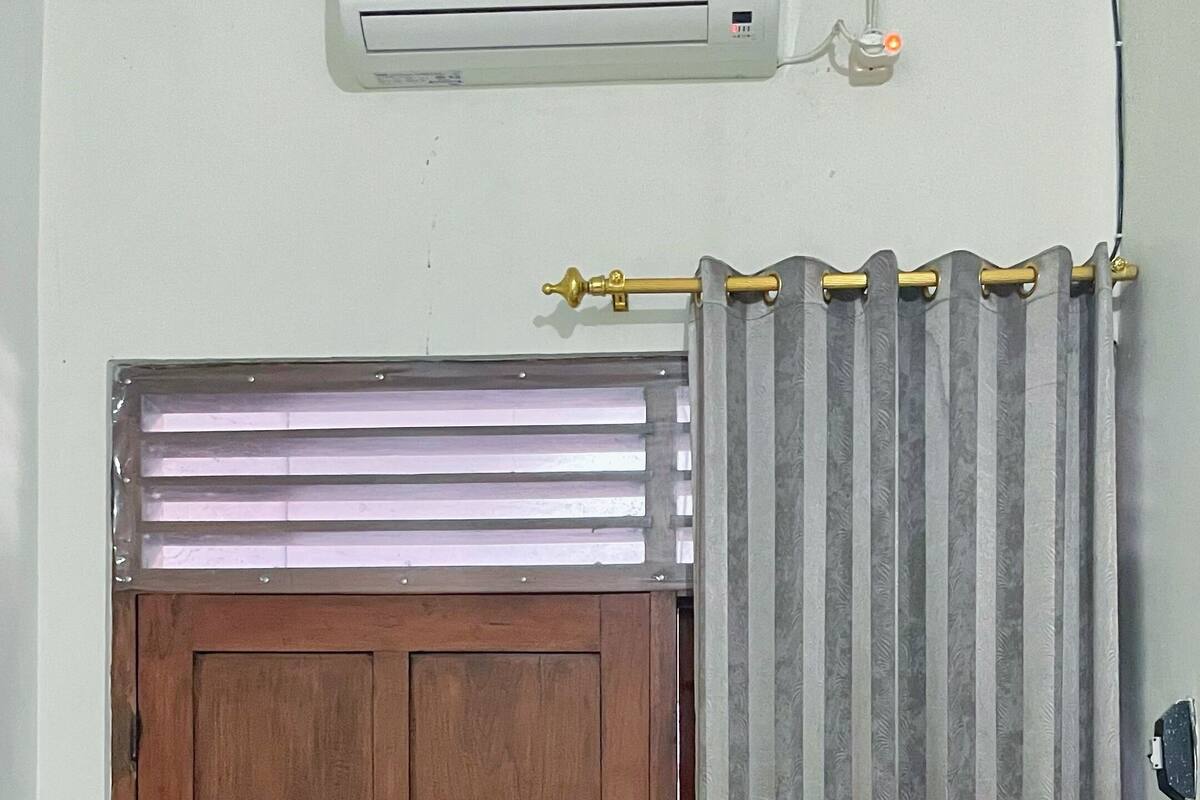 A wooden door with a window above it, a curtain, and an air conditioning unit on the wall.