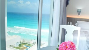 A hotel room with a large window overlooking a beach and ocean. - Brand new studio at the beach, gym, pool, jacuzzi, spa (Cancún)