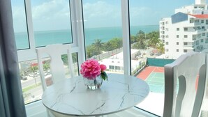A room with a large window, a white marble table, and a vase with pink flowers. - Brand new studio at the beach, gym, pool, jacuzzi, spa (Cancún)