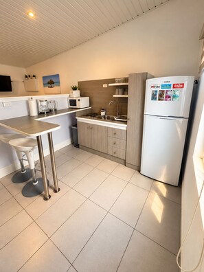 A compact kitchen with a white refrigerator, a coffee maker, a microwave, and a sink. - Paradise Studio Aruba (Oranjestad)