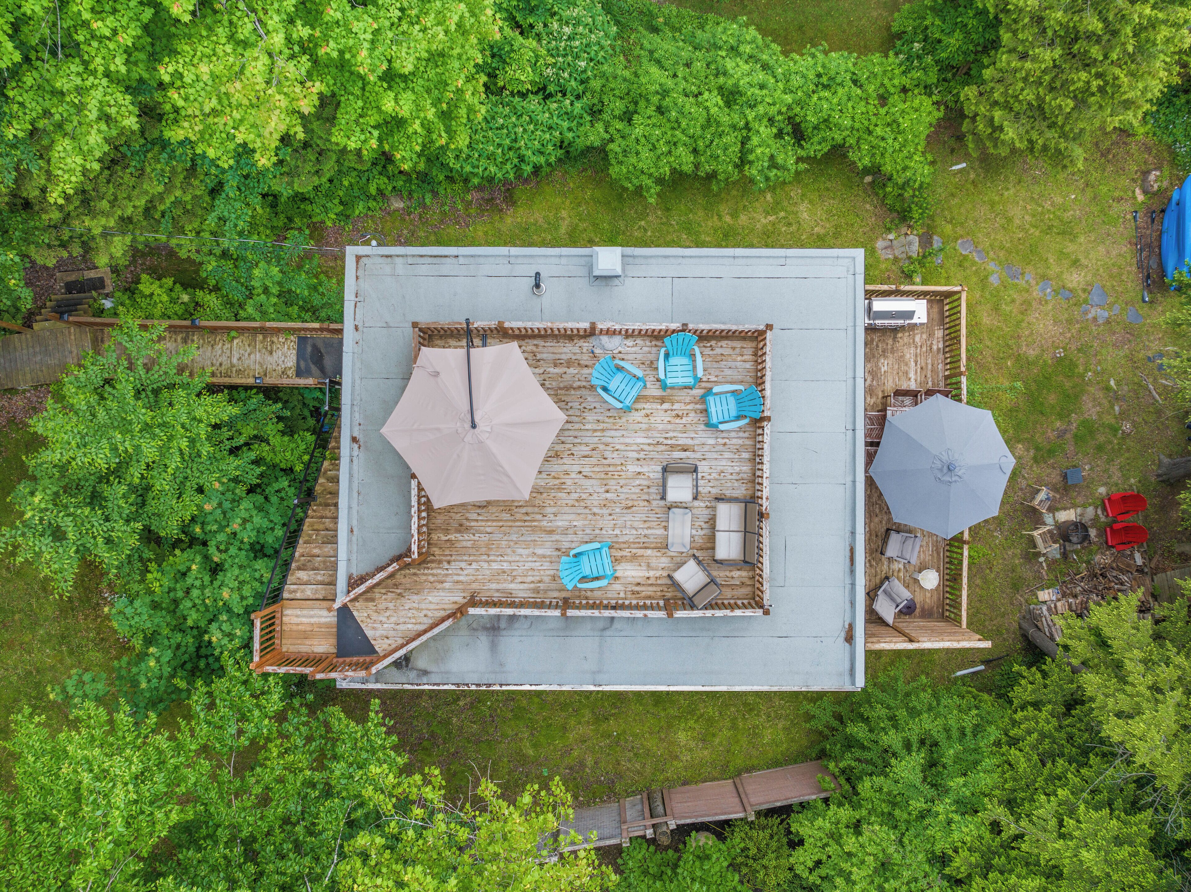 An aerial view of a deck with a seating area, two umbrellas, and a small outdoor kitchen.