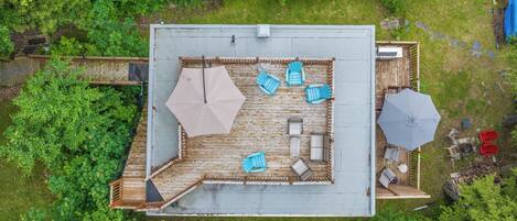 An aerial view of a deck with a seating area, two umbrellas, and a small outdoor kitchen.