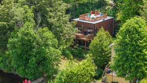 Ein zweigeschossiges Haus mit einer Terrasse, umgeben von dichtem Wald.
