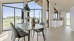 Un vaste espace dédié à la salle à manger, comprenant une grande table, des chaises et un luminaire suspendu.