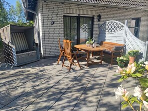 A patio with a table and chairs, a wooden bench, and potted plants.