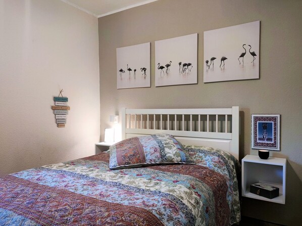 A bedroom with a bed, a nightstand, a wall-mounted shelf, and three wall art pieces depicting birds.