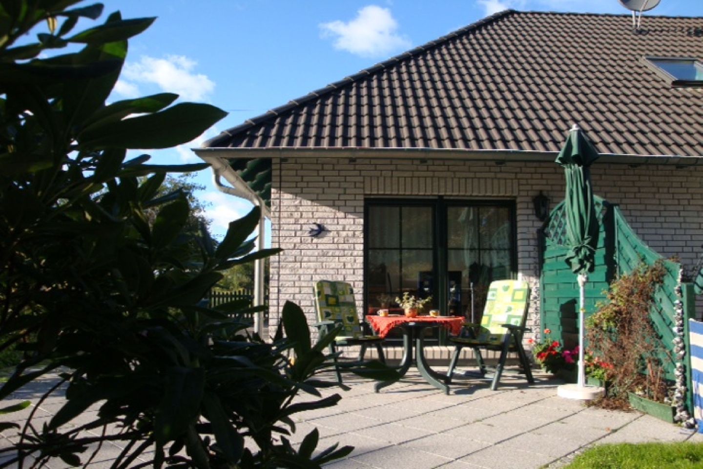 Een huis met een pannendak, een bakstenen gevel en een patio met een tafel en stoelen.
