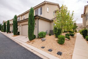 Una calle residencial con casas de color beige, aceras y áreas ajardinadas con árboles y arbustos.
