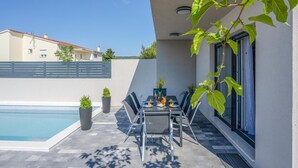 A patio with a pool, a table set for two with drinks, and potted plants. - Amazing home in Vodice with WiFi (Vodice)