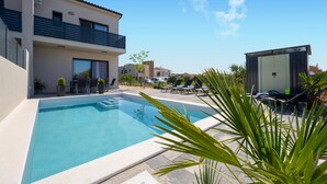 A swimming pool with lounge chairs, a small building, and a two-story house with balconies. - Amazing home in Vodice with WiFi (Vodice)