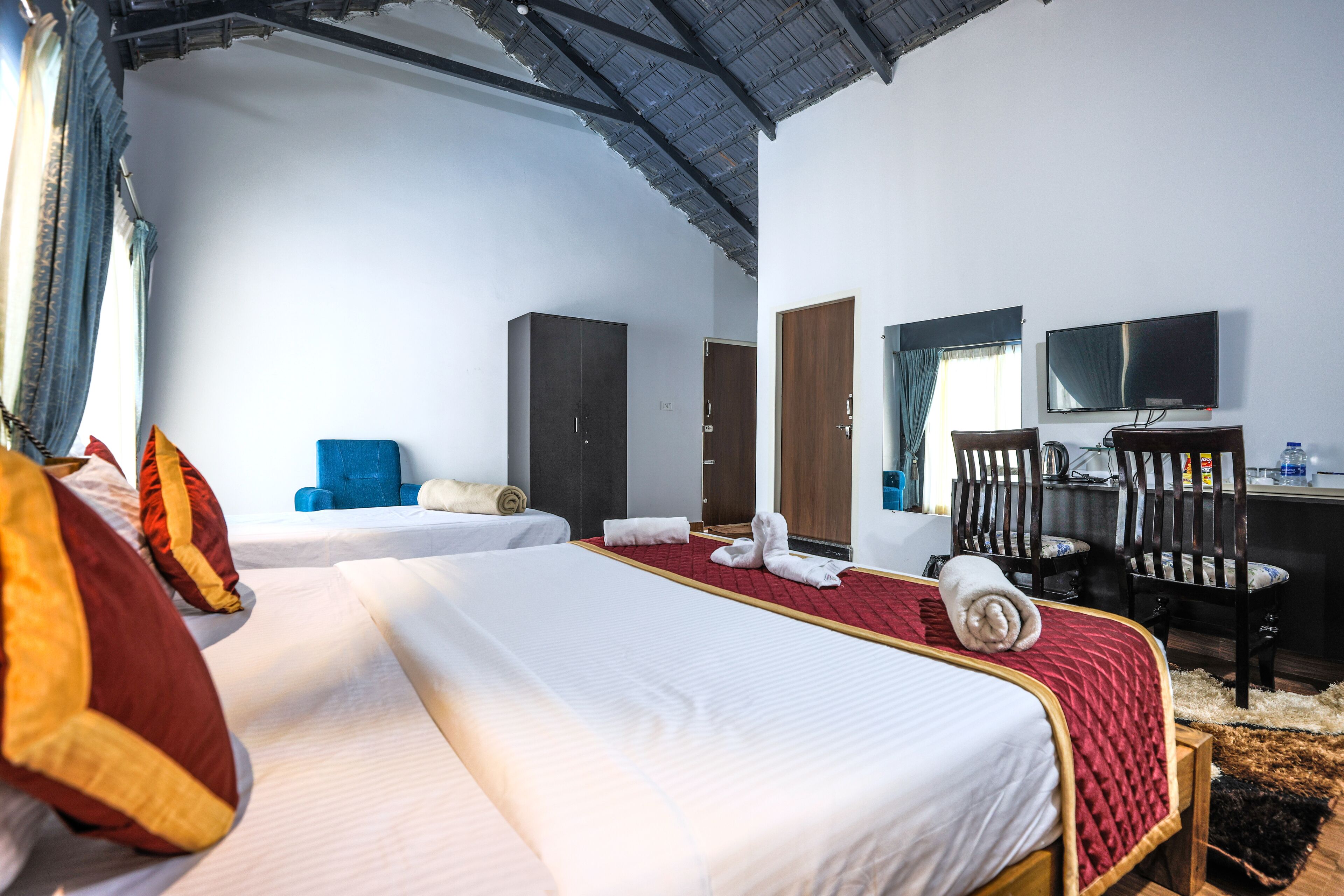 A hotel room with two beds, a desk, a chair, a television, and a wardrobe.