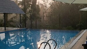 Een zwembad met helder water, omgeven door stenen tegels en een houten terras.