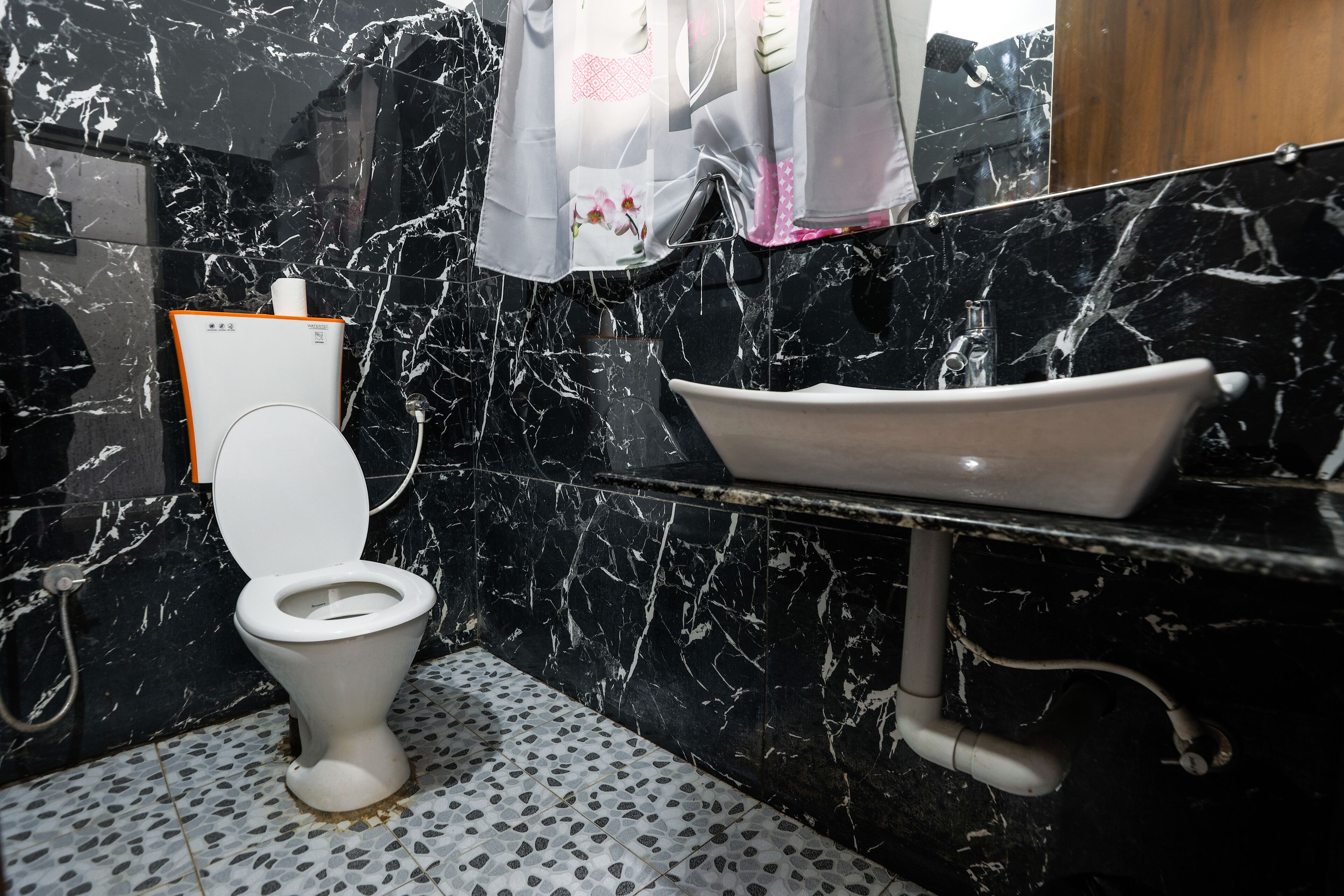 Un baño con inodoro, lavabo y zona de ducha.
