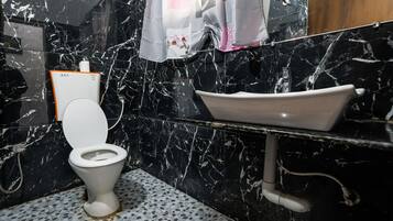 A bathroom with a toilet, a sink, and a shower area.