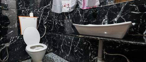Un baño con inodoro, lavabo y zona de ducha.