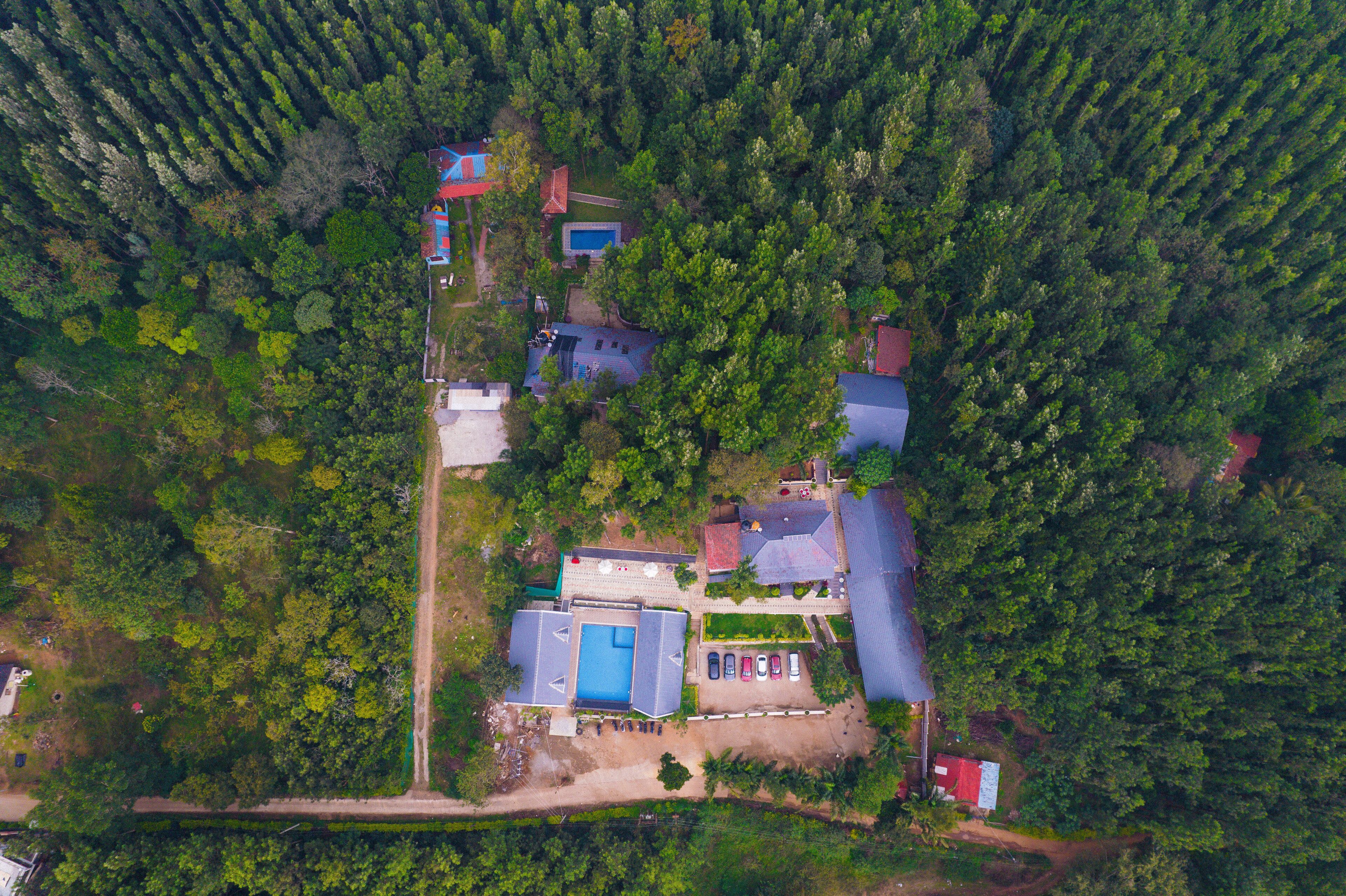 Vista aérea de un barrio residencial con varias casas, una piscina y un edificio rojo.