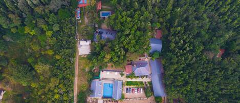 An aerial view of a residential area with multiple houses, a swimming pool, and a red building.
