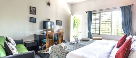 A hotel room with a bed, a desk, a chair, and a television.