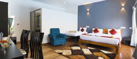 A modern hotel room with a bed, two chairs, a dining table, and a large mirror.