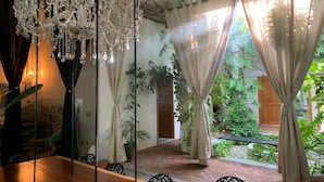 An indoor dining area with a wooden table and chairs, a chandelier, and large windows with curtains. - Casa Lucía Natural (Santa María Huatulco)
