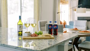 A kitchen counter with a bottle of wine, two glasses of wine, a cutting board with cheese, olives, and grapes, and two bottles of Pepsi. - Amazing 3 BR Home | 5 mins to DT | Pet Friendly (New Bern)