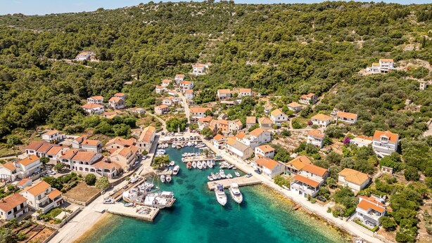 Un pueblo costero con casas, un puerto deportivo y un paisaje montañoso.